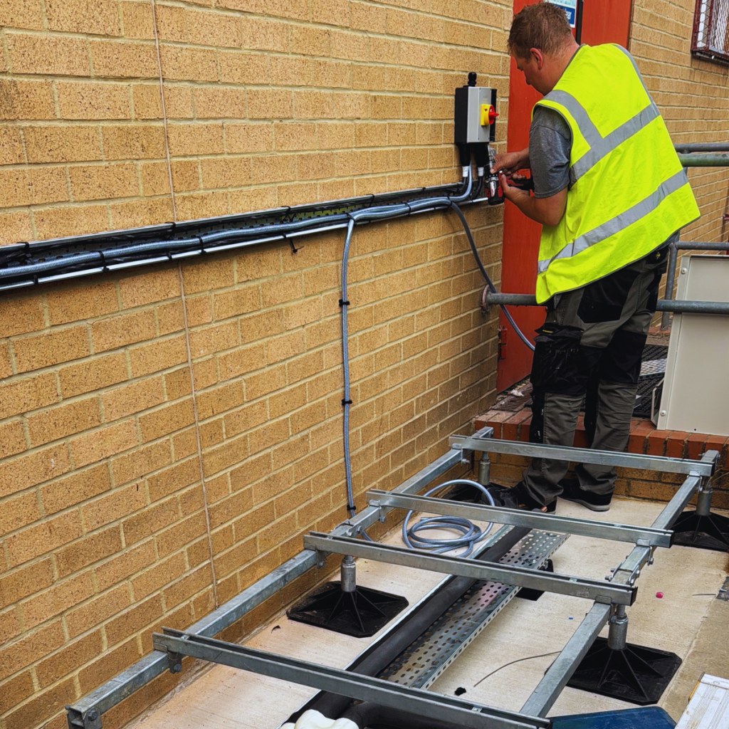 HVAC engineer installing external pipework and services on a commercial site